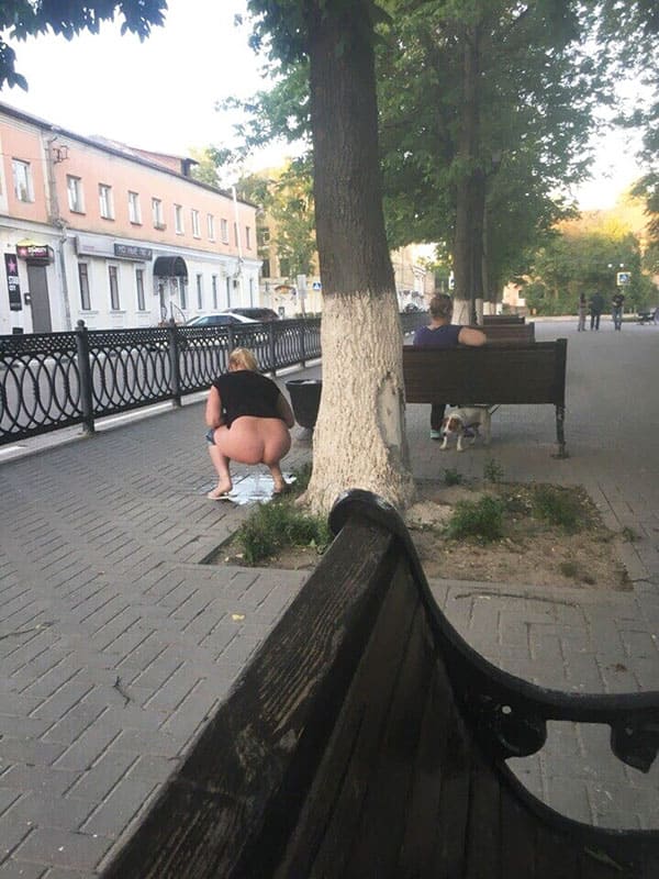 Женщина с голой жопой ссыт на корточках посреди бульвара прямо за скамейкой с людьми